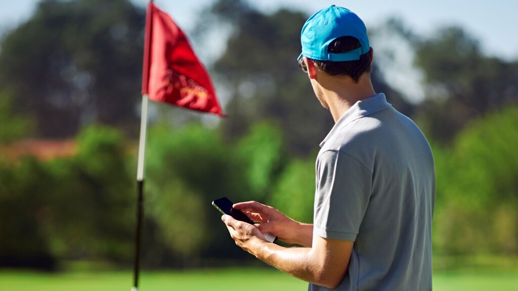 User on golf course referencing phone